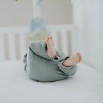 Cute baby feet in pajamas on a soft white crib. Perfect for children's room decor.