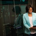 Female IT professional examining data servers in a modern data center setting.