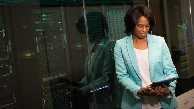 Female IT professional examining data servers in a modern data center setting.