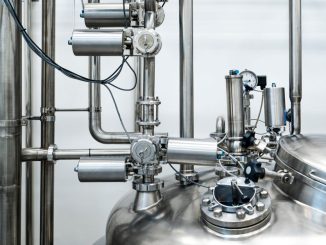 Close-up of stainless steel machinery and pipes in an industrial setting, showcasing modern engineering.