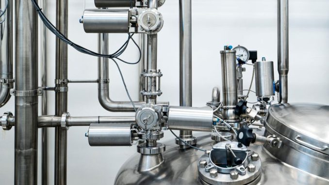 Close-up of stainless steel machinery and pipes in an industrial setting, showcasing modern engineering.
