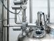 Close-up of stainless steel machinery and pipes in an industrial setting, showcasing modern engineering.