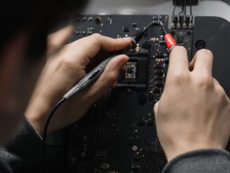 Close-up of hands repairing a circuit board using a soldering iron, emphasizing technical skill.